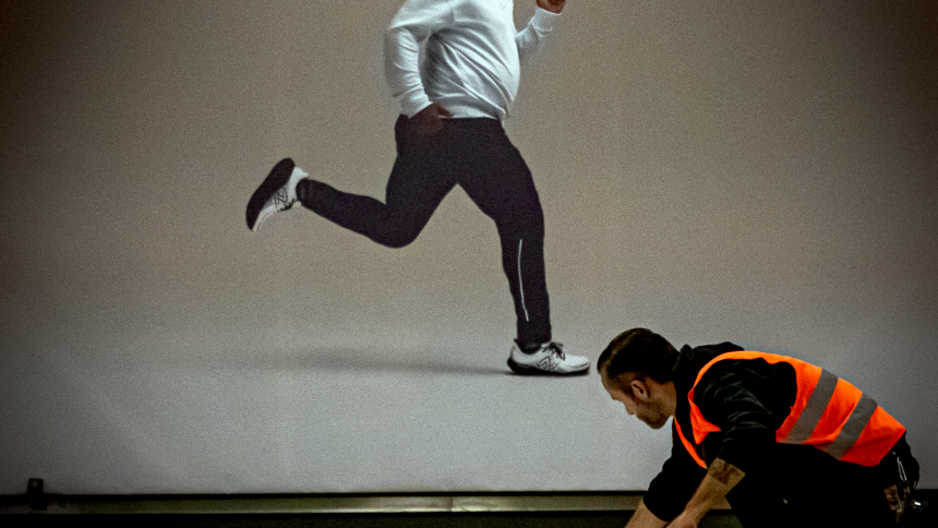 Poster of a running man juxtaposed with a man wearing an orange worker's vest